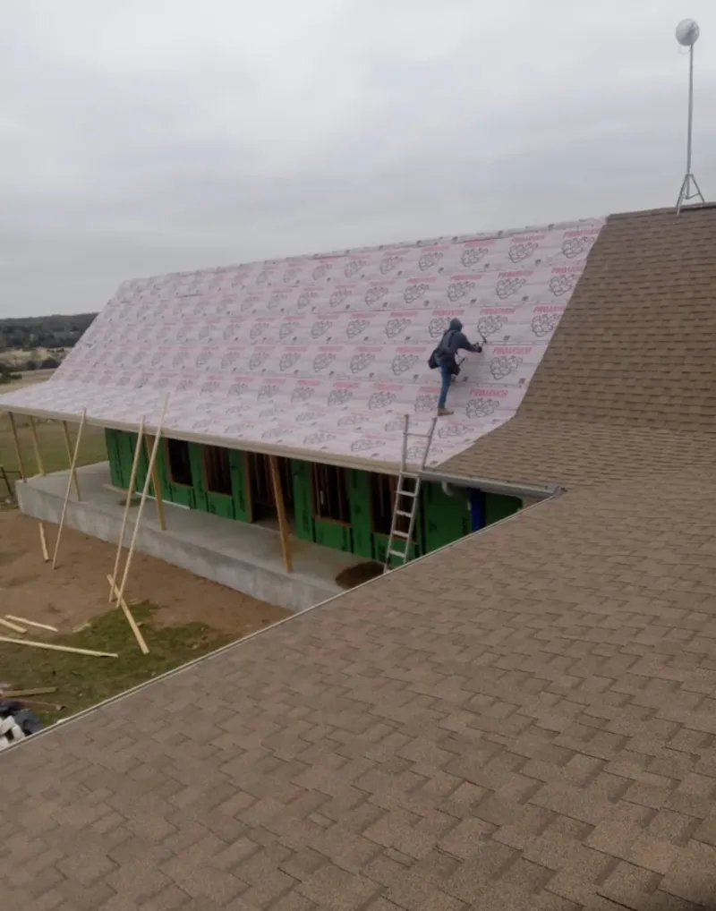 Worker preparing underlayment for a metal roof installation in Hiawatha